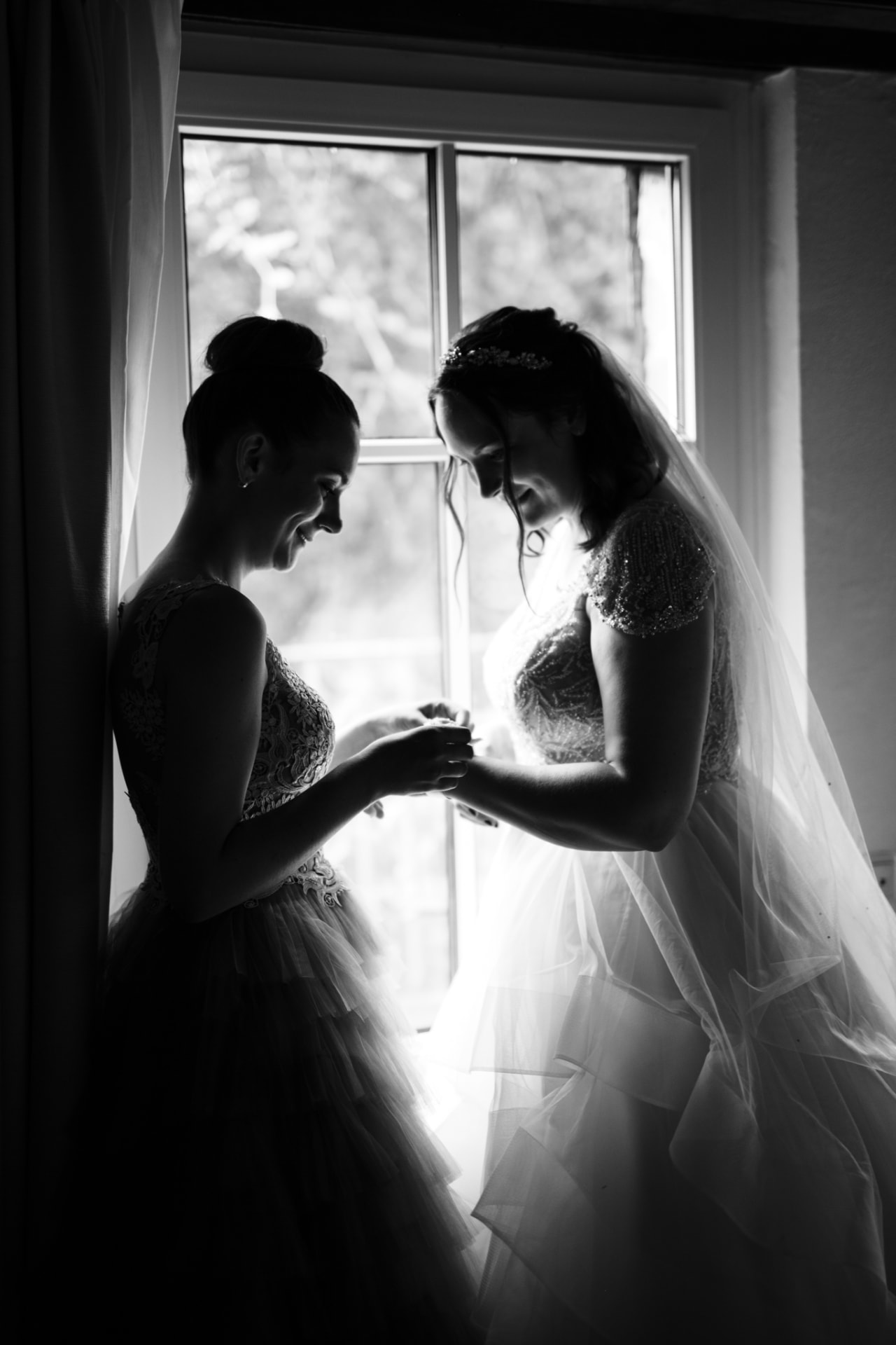 Braut und Trauzeugin am Fenster in Schwarzweiß — Hochzeitsfotografie Ostbelgien